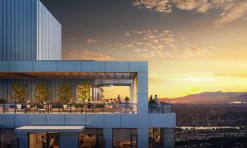 A modern building with a balcony overlooking a cityscape at sunset.